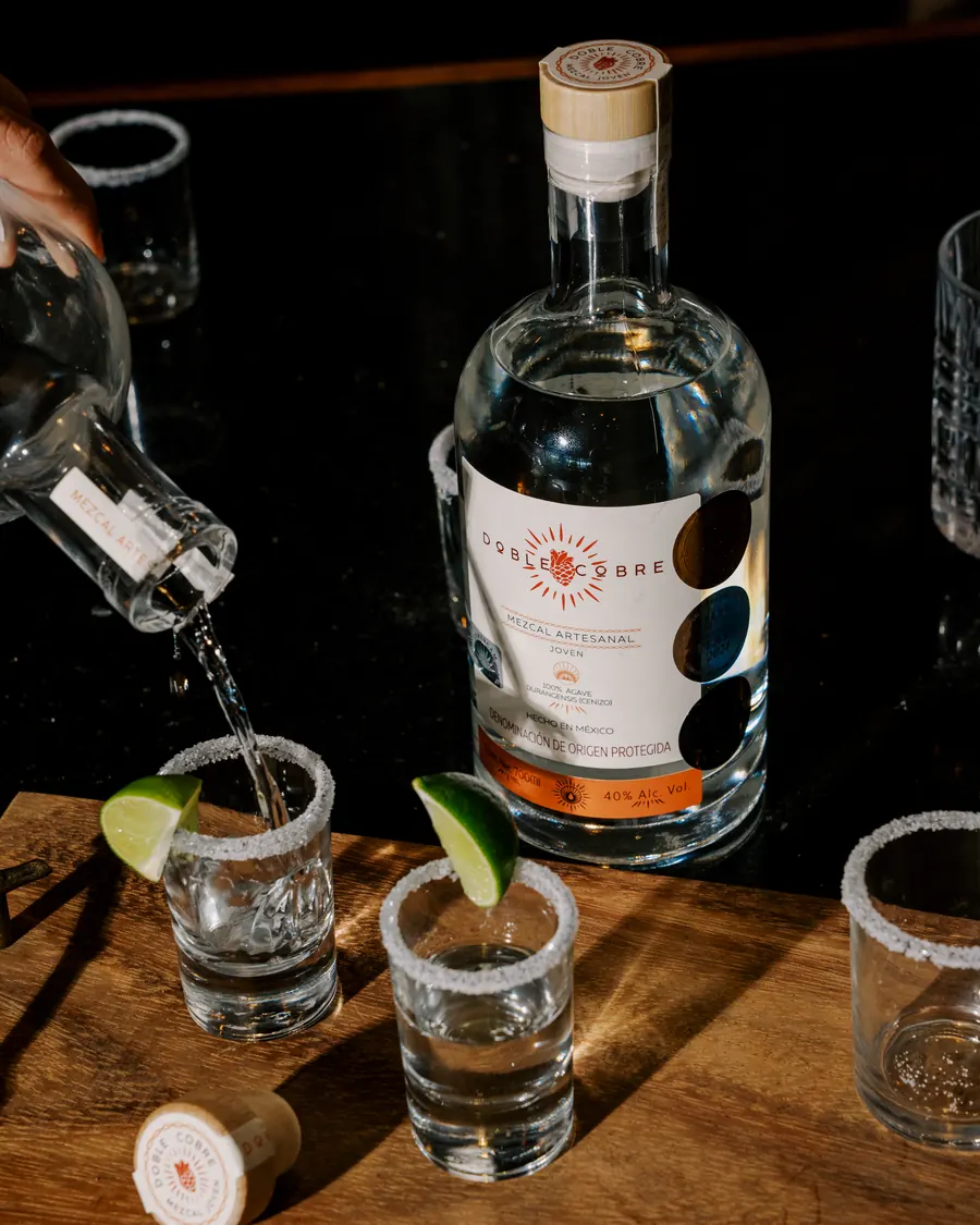 Mezcal Doble Cobre sirviéndose en caballitos escarchados con limón