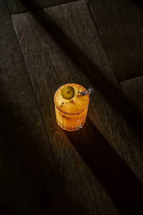 Coctel de mezcal con hierbas bajo la luz del atardecer