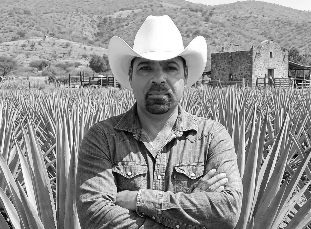 Mauro Débora Escobar, maestro mezcalero, con sombrero y los brazos cruzados entre agaves en Nombre de Dios, Durango
