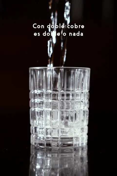 Mezcal servido en un vaso de cristal con la frase: con Doble Cobre es doble o nada