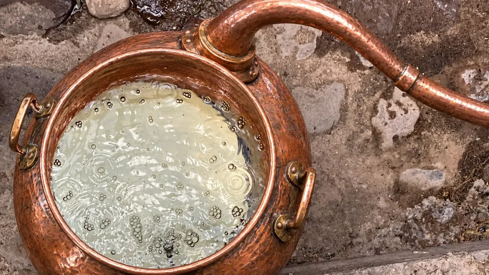 Alambique de cobre martillado visto desde arriba, con el líquido burbujeando durante la destilación